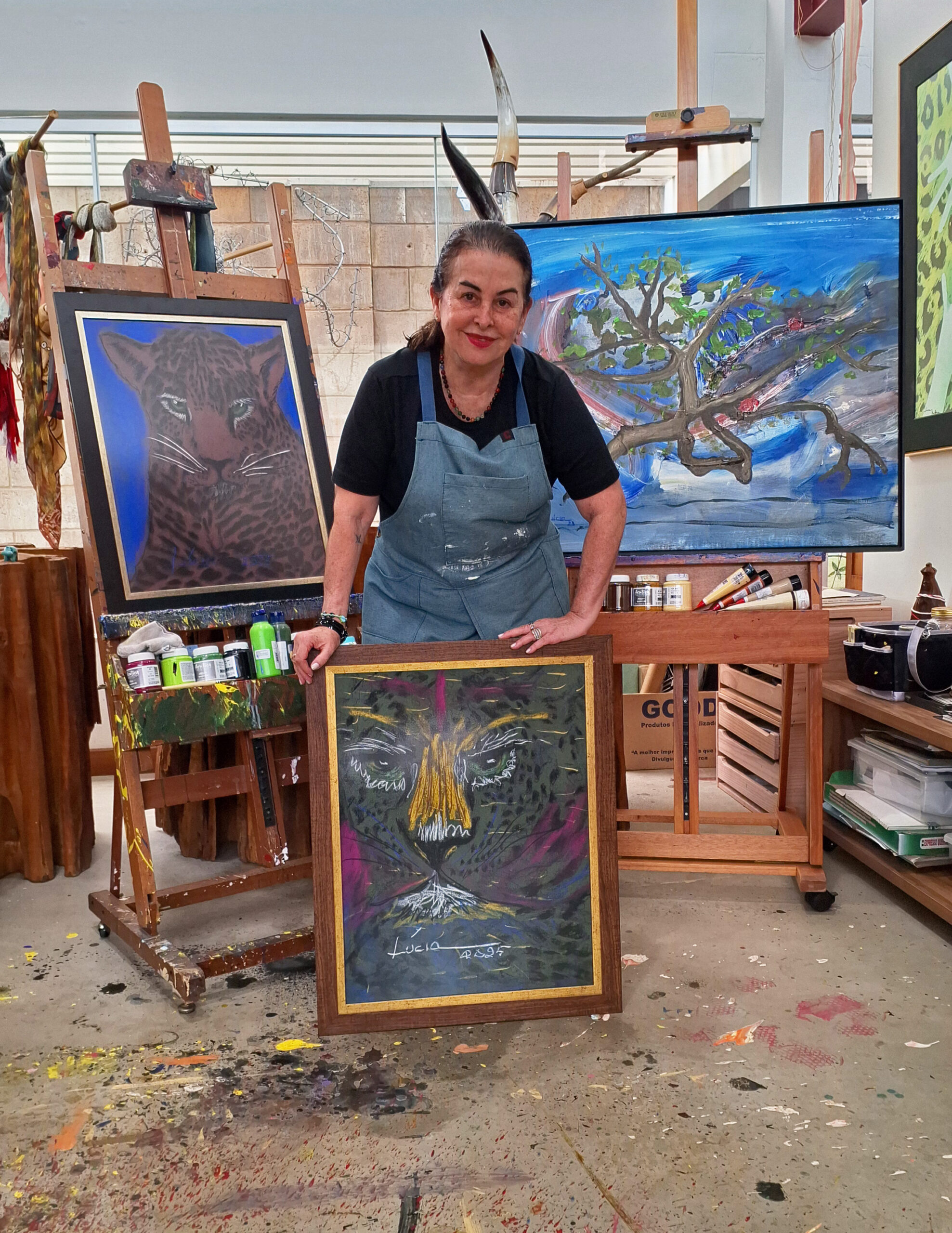 A artista com três de suas obras, duas delas com onças, sua marca registrada