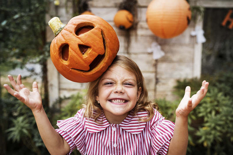 Young playful girl with her Halloween jack-o'-lantern